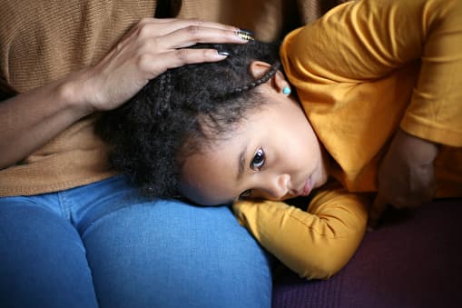 A child with a stomache takes comfort in their parents lap.